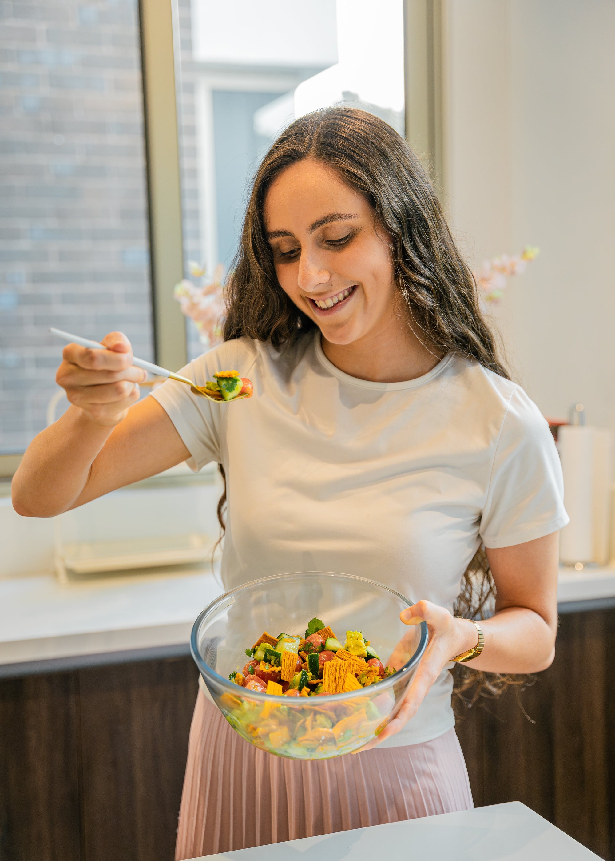 Women holding a bowl and eating a salad