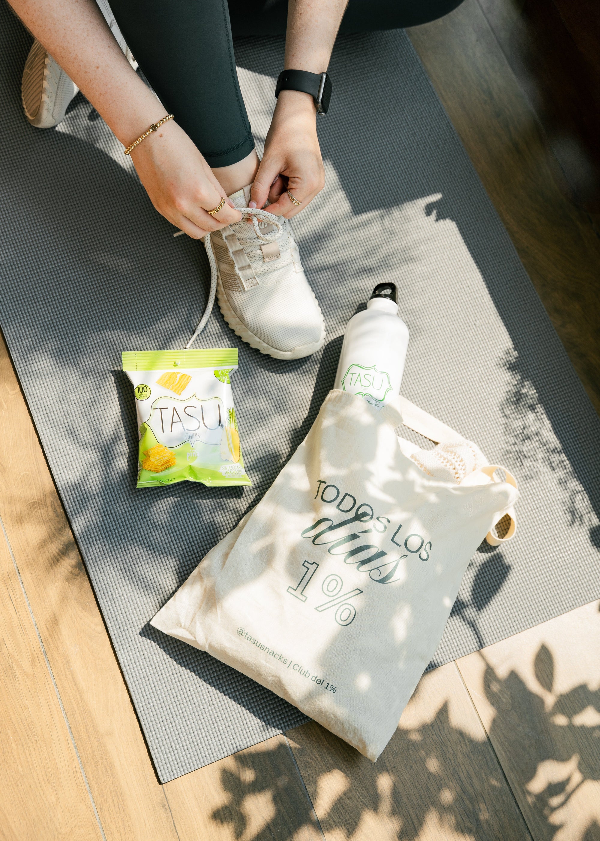 Woman over a mat with a TASU bag and water bottle and 