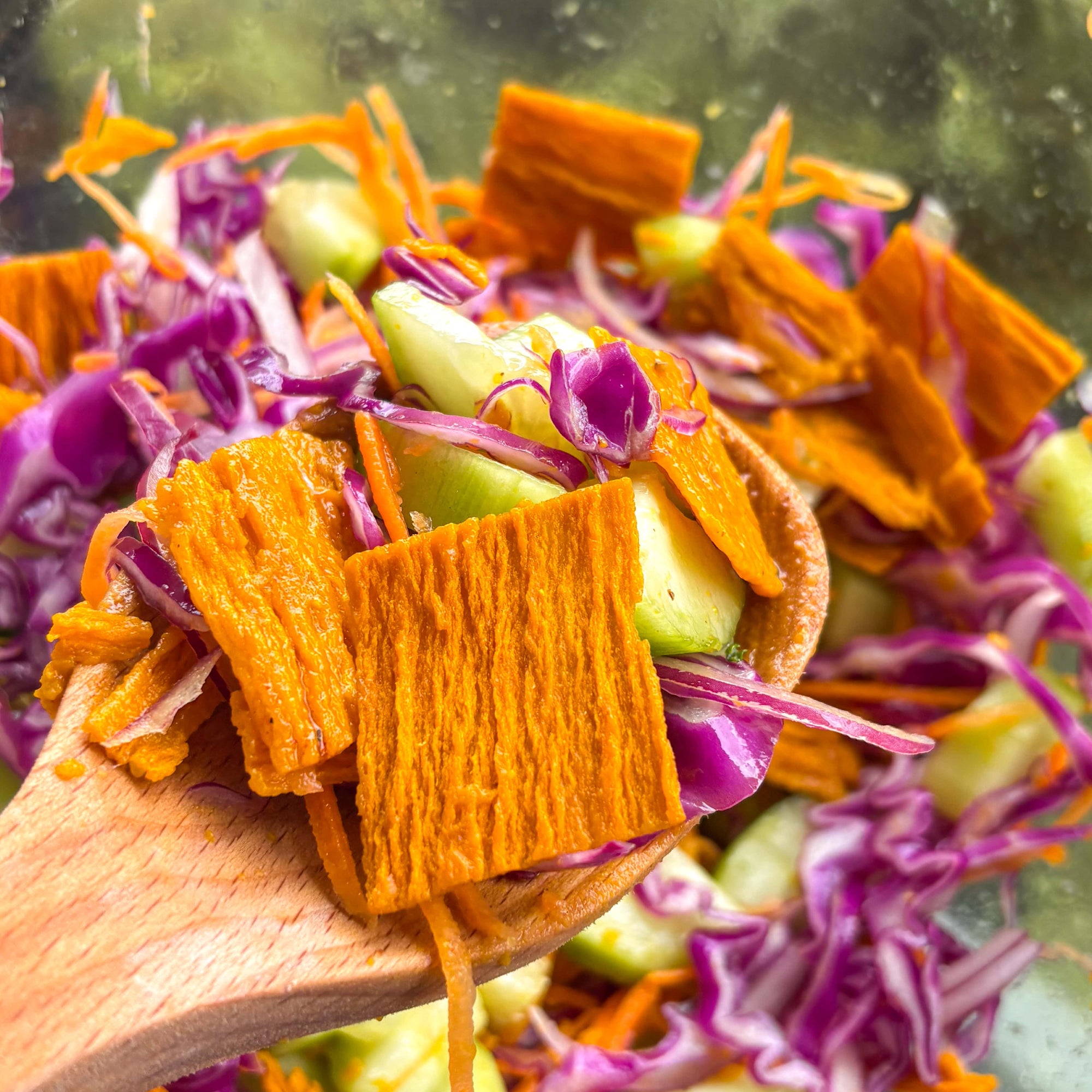 Cucumber mango slaw salad over a wooden spoon