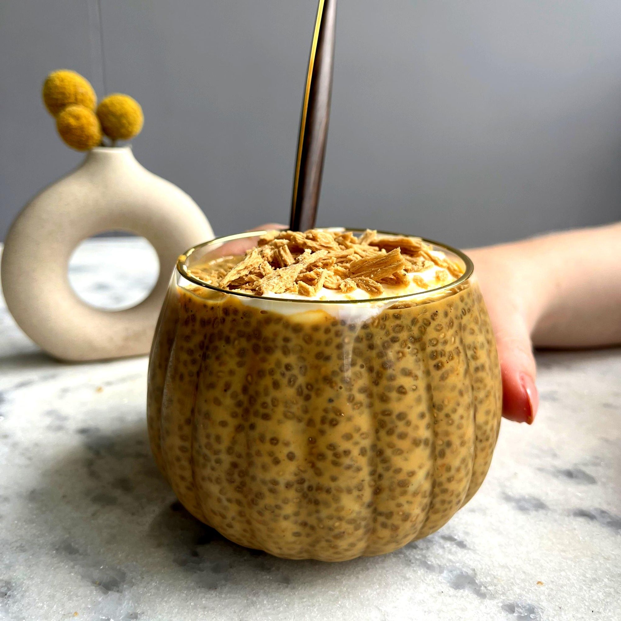 Pumpkin banana chia pudding in a glass bowl and a spoon